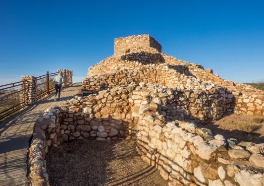 Guest walking towards stone ruins, other stone structures to her right.