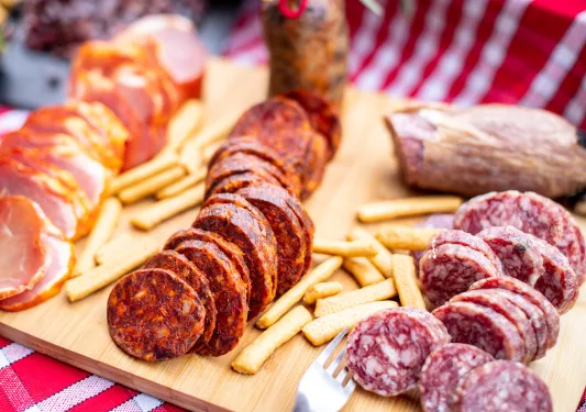 Snack board with cured meats and crackers.
