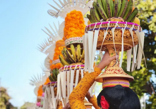 Procession of beautiful Balinese women in traditional costumes - sarong, carry offering on heads for Hindu ceremony.