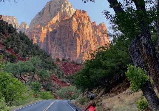 Biker on road looking back towards mountain