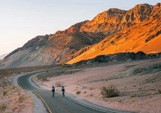 Guests riding down desert road during sunset.
