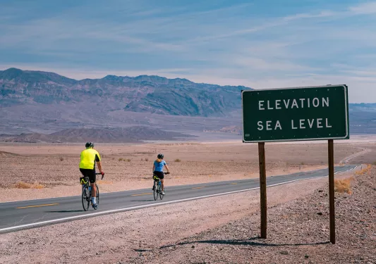 Cyclists on the road in California desert Elevation Sea Level sign