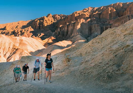 Guests hiking among craggy,, amber desert hills.