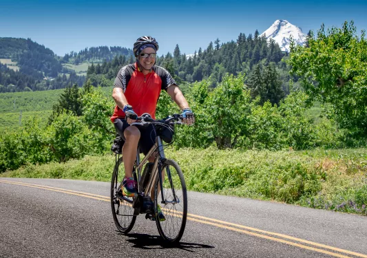 Guest cycling up grassy road, mount hood for off in background.