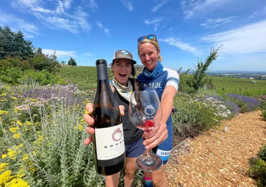 Two guests/leaders showing a wine bottle and glass to the camera.