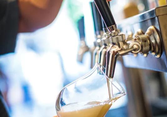 Close-up of a man pouring beer from a tap.