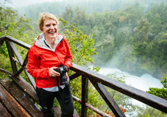 Backroads guest holding DSLR camera in rainy jungle landscape.