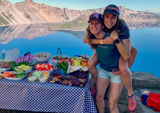Two guests/leaders next to lunch spread, one is on the other's back.