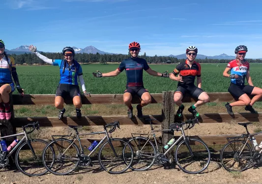 Five guests and their bikes, sitting on a large fence.
