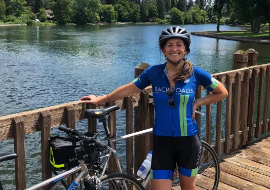 Guest posing on wooden bridge, lake or river in background.