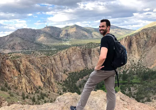Guest standing on cliff's edge overlooking Smith Rock Park.