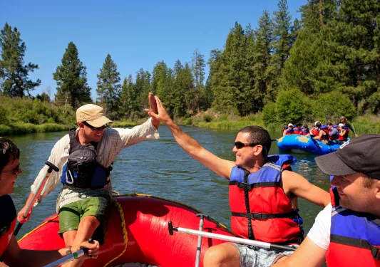 Two guests hi-fiving on rafts.