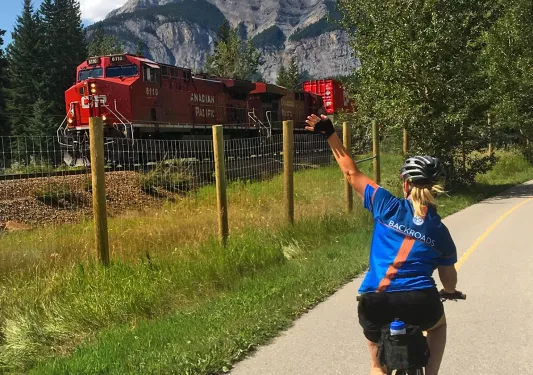 Guest cycling past train, waving to it.