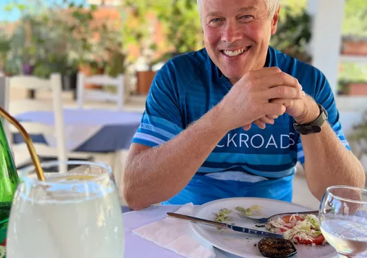 Guest in bike gear at meal, smiling at camera.