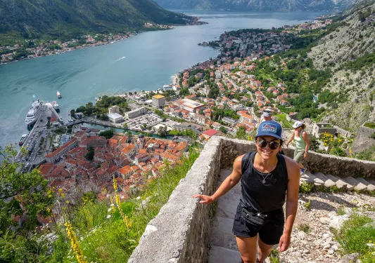 Two guests walking up stone staircase, Croatian village, river below them.