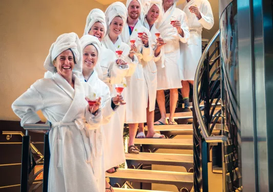 Backroads guests lined up in a row on a set of stair, all in white robes and towels on heads.