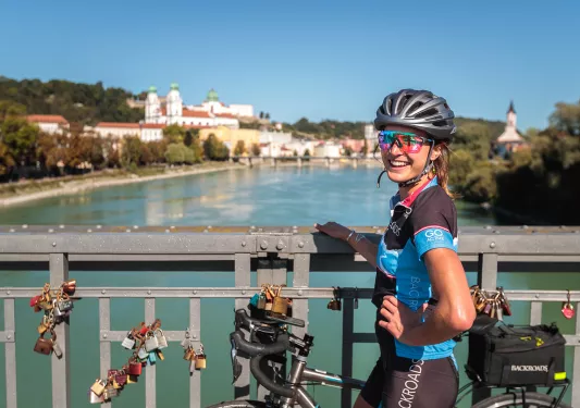 Biker posing on the bridge railing across the Danube River.