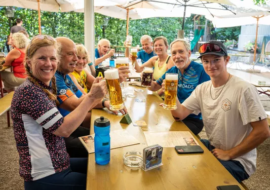 Guests sitting around a table holding pints of beer.