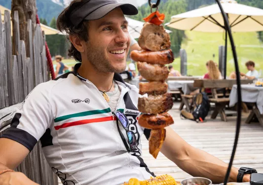 Guest/leader at meal, hanging shish kabob(?) with potato wedges in front of them.