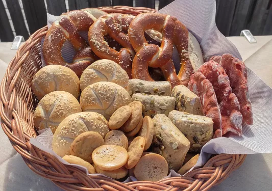 Basket filled with different types of bread and rolls, soft pretzels.