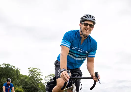 Ground-level shot of guest cycling, smiling at camera.