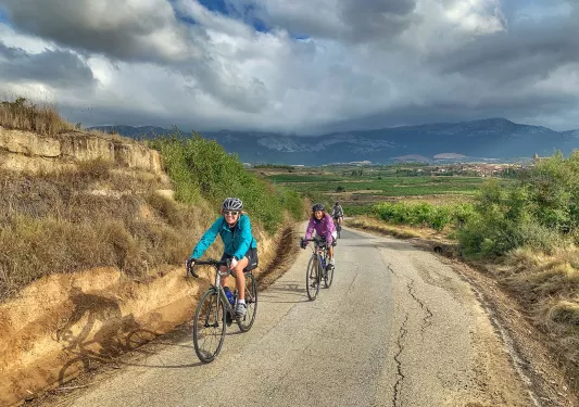 Two bikers cycling on a road in Spain.