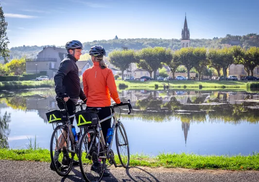 Two guests with bikes looking out towards river, town, hills, church spire.