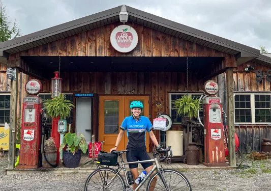 Guest with bike standing in front of "THE APPLE STATION".
