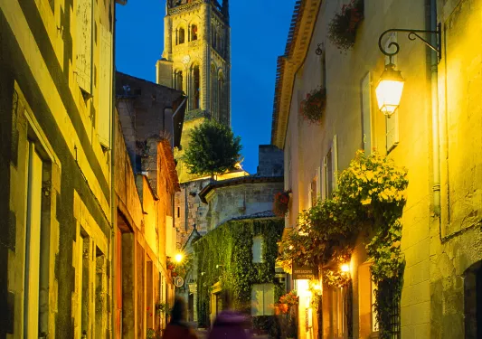 Two guests walking down French alleyway, church spire in front of them.