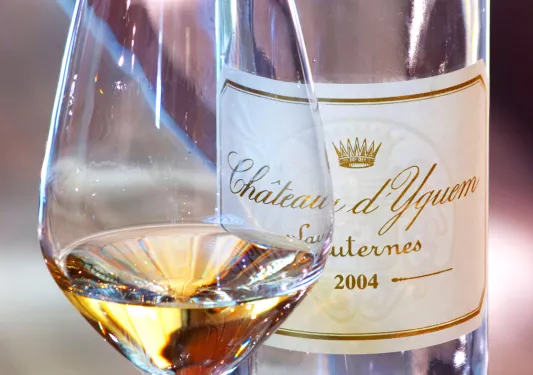 Close-up of white wine glass, bottle.