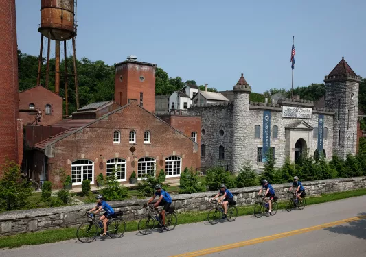 Five guests cycling past the "OLD TAYLOR DISTILLERY COMPANY" and it's brick buildings.