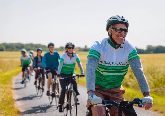 Close-up of line of cycling guests, golden meadow behind them.