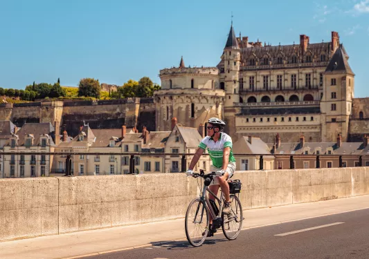 Guest cycling in French town, Château Royal d'Amboise in background.