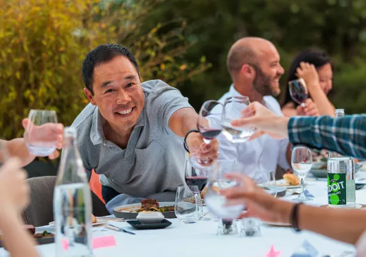 Guests at dinner table, cheersing wine glasses.