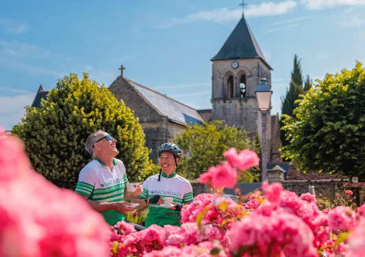 Two guests in flower garden, church behind them.