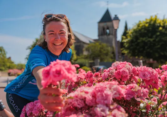 Guest handing camera pink flowers, church behind her.