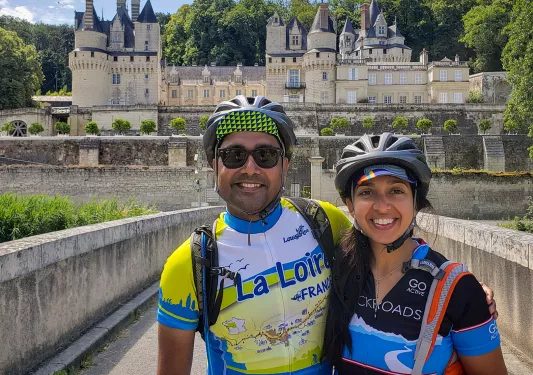 Two guests in bike gear posing in front of Château d'Ussé.