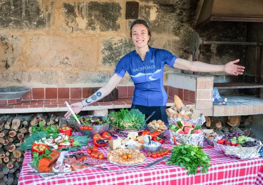 Backroads leader posing with table of Spanish food and snacks.