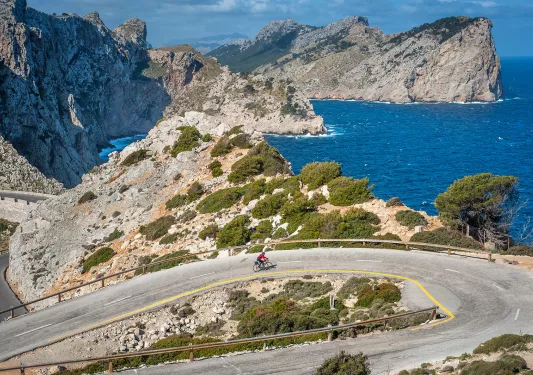 Biker riding around a bend on the coast of Mallorca.