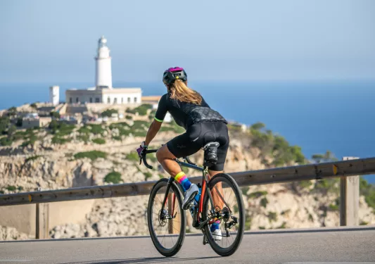 Biker riding on a road along Mallorca coast, with church tower in Background.