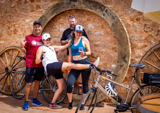 Bikers posing with their bikes and glasses of wine.