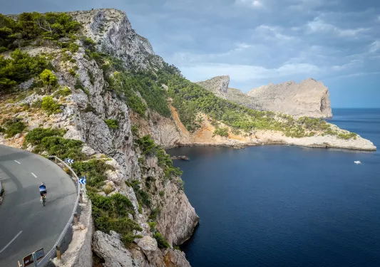 Biker riding around a bend on the coast of Mallorca.