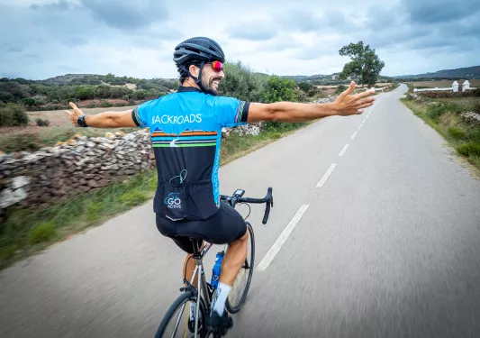 Biker riding on a road with hands in the air.