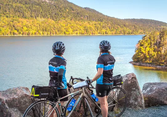 Two guests with bikes overlooking large body of water.