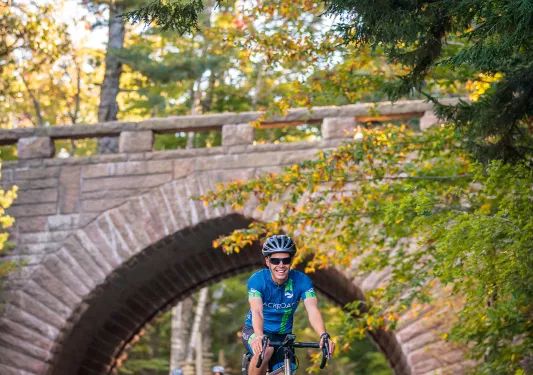 Guests biking under brick bridge.