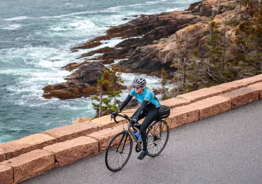 Guest biking on road, rough ocean water in background.
