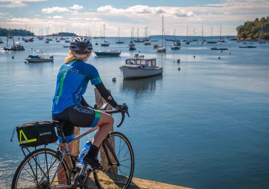 Guest with bike on pier, overlooking bay full of sailboats.