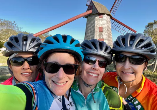 Group of four guests in glasses, windmill behind them.