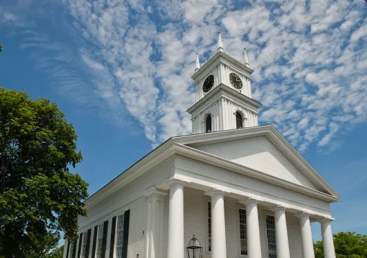 White colonial building with small clock tower.