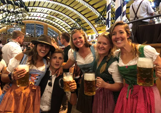 Four people in traditional German dirndels having pints of beer.